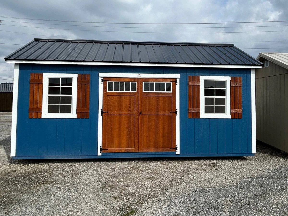 Blue-painted shed with white trim, wood window shutters, and stained wood double doors with a transom