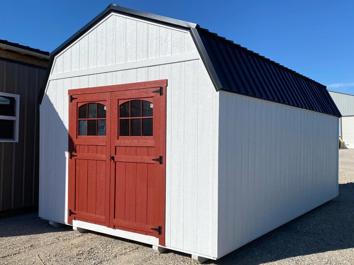 White barn-style shed with a gambrel roof and red double doors
