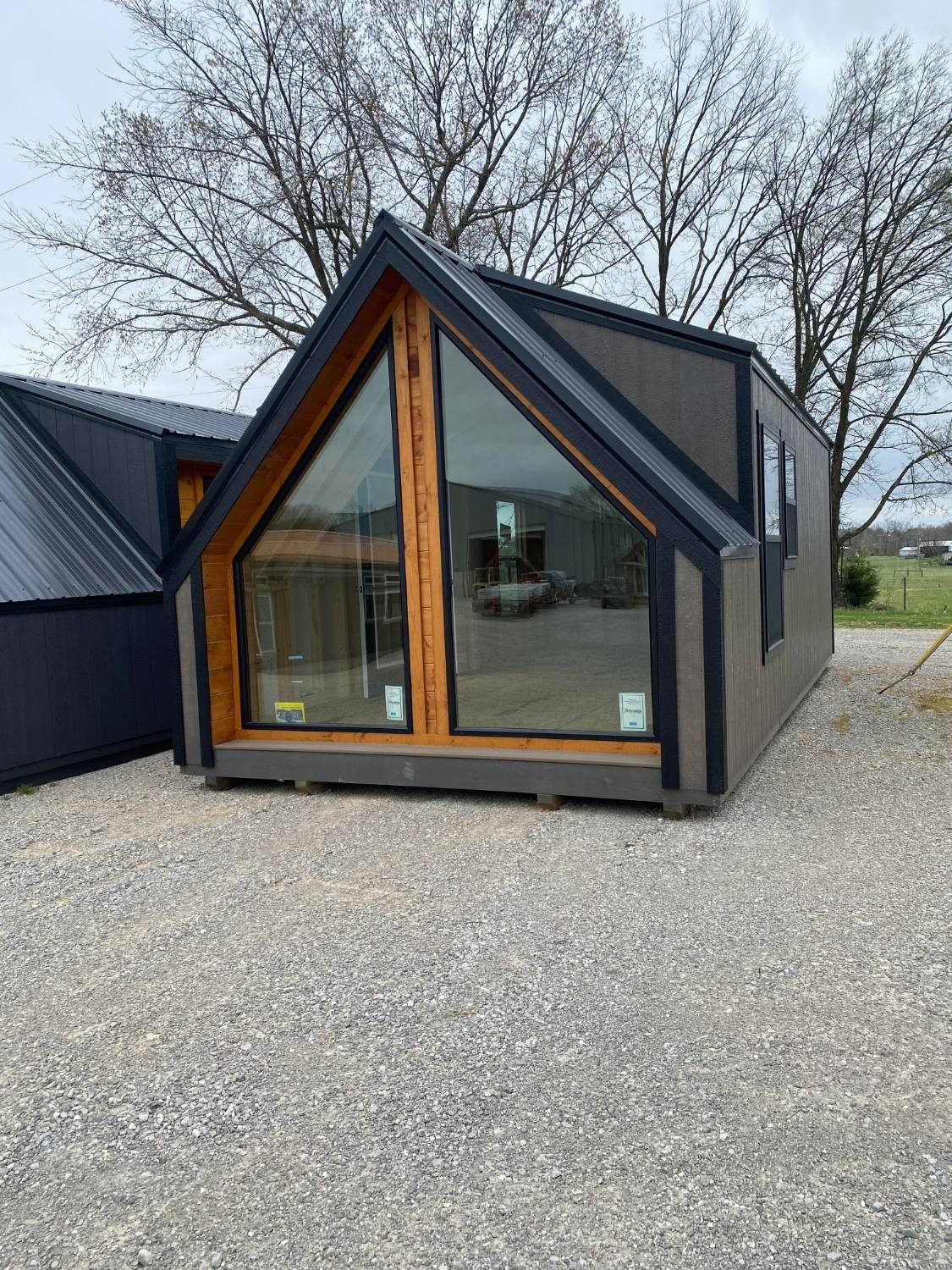 Gray A-frame tiny home with a large glass gable window and black trim