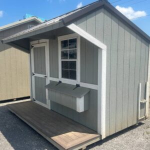 Small gray wooden shed with white trim, a front porch, and a single window.