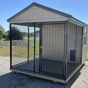 Outdoor metal‑grid dog kennel on a wooden platform, set on a gravel lot under a clear blue sky