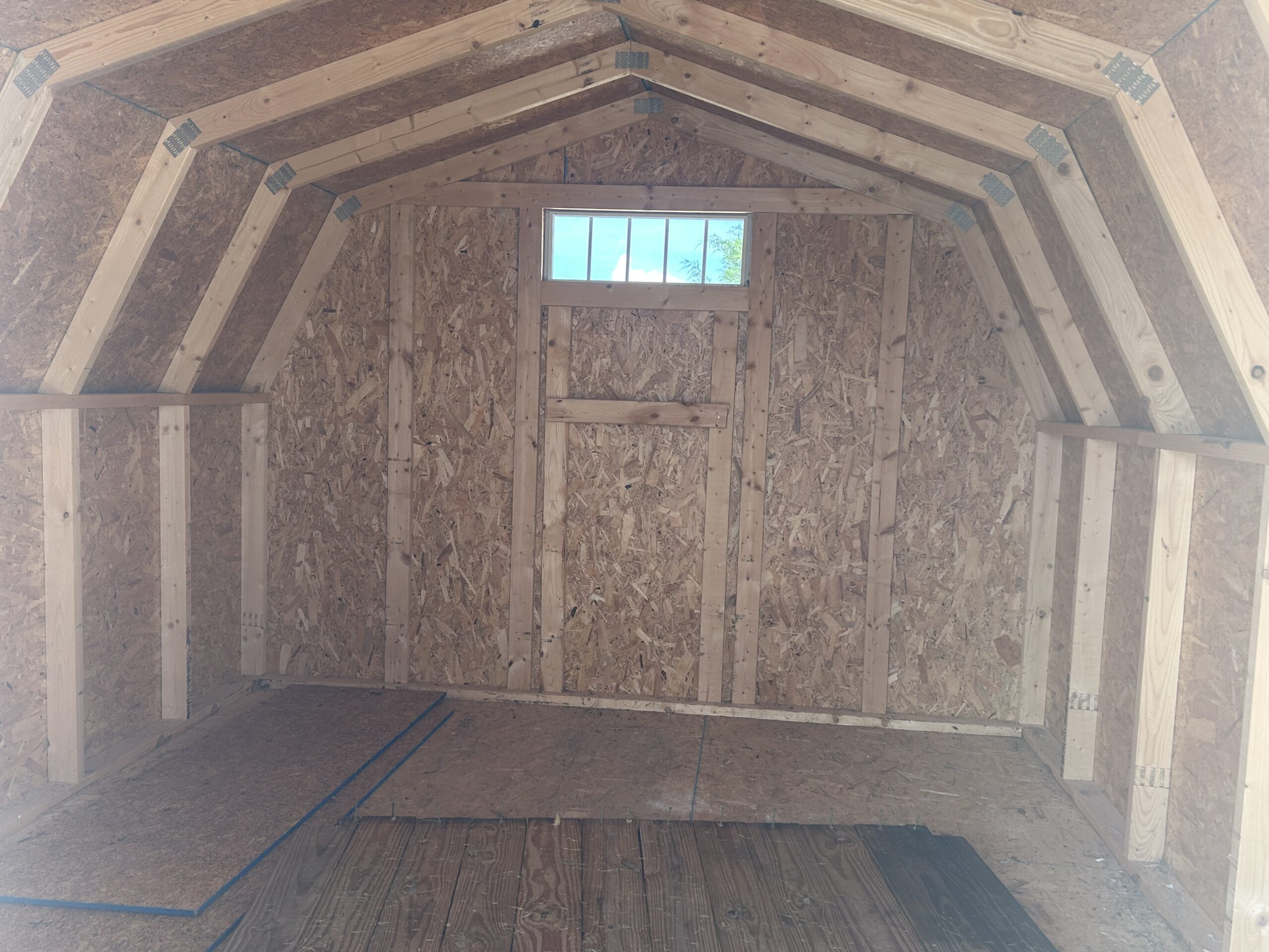 Unfinished attic with exposed wooden framing and a small window at the far end.