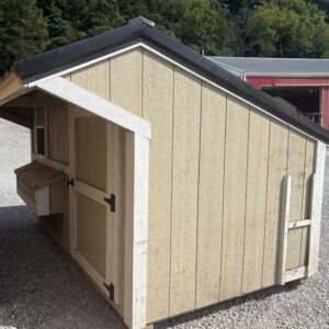 Beige wooden shed with a black sloped roof on a gravel lot, open counter shelf visible on the side, red building in the background.